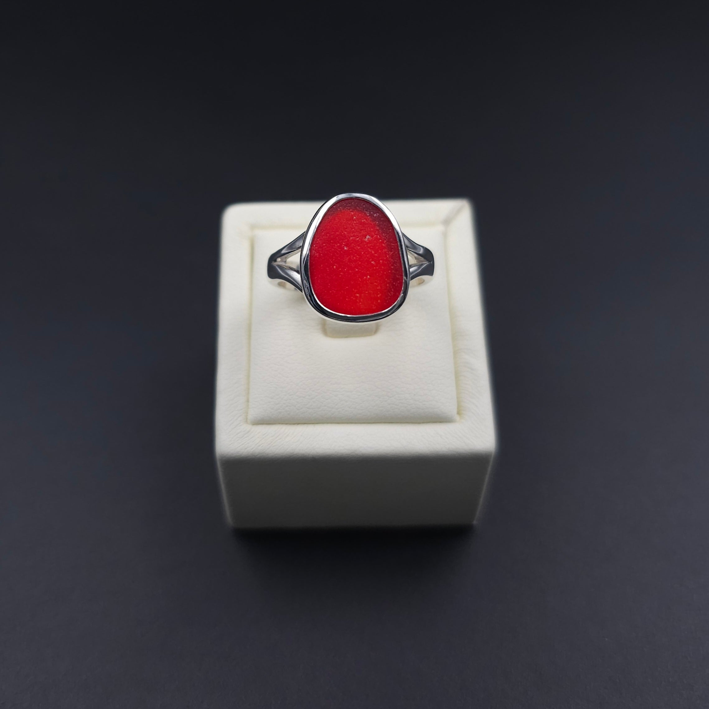 Silver ring with rounded traingle shaped red sea glass bezel set. 
