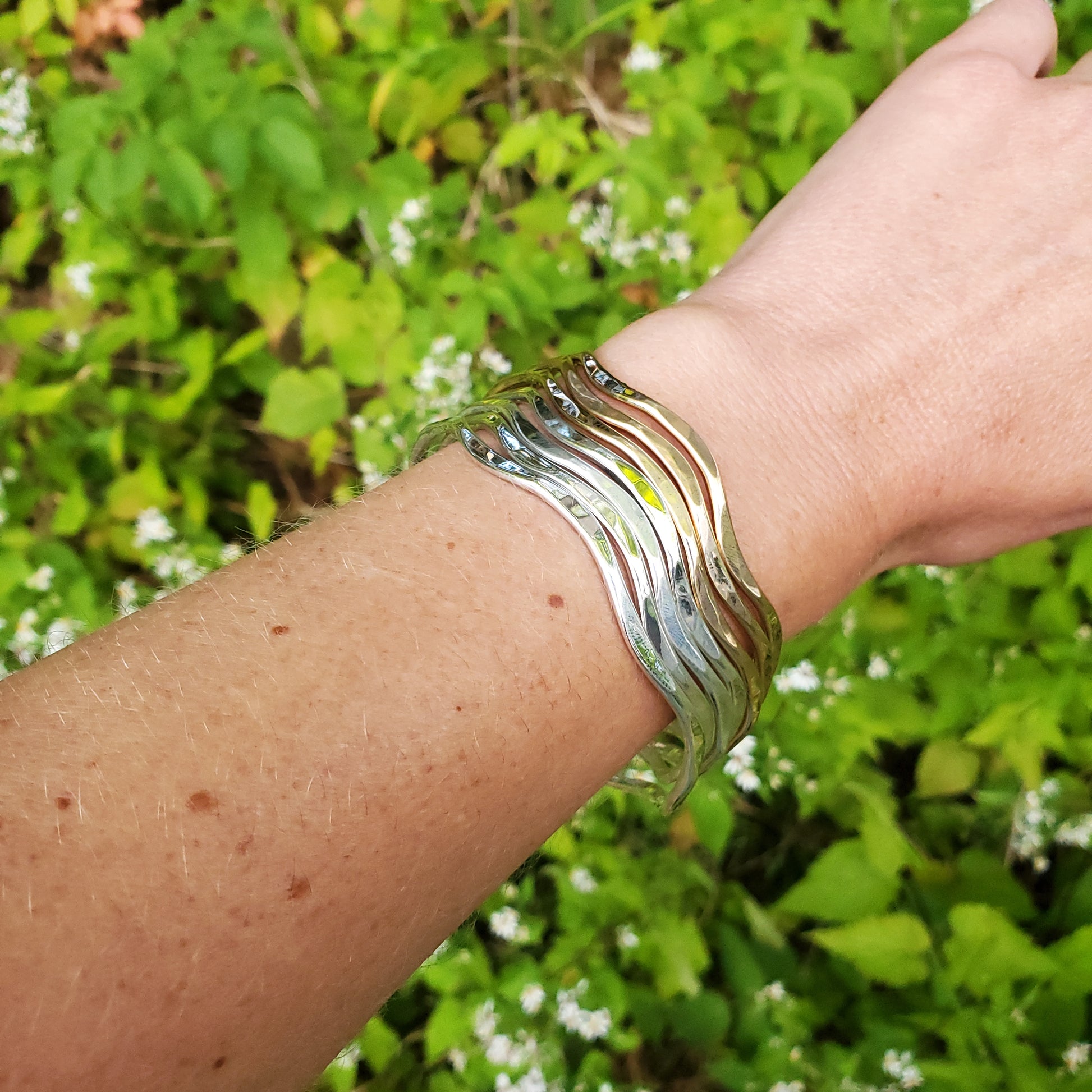 Several wavy cuff bracelets shown on wrist