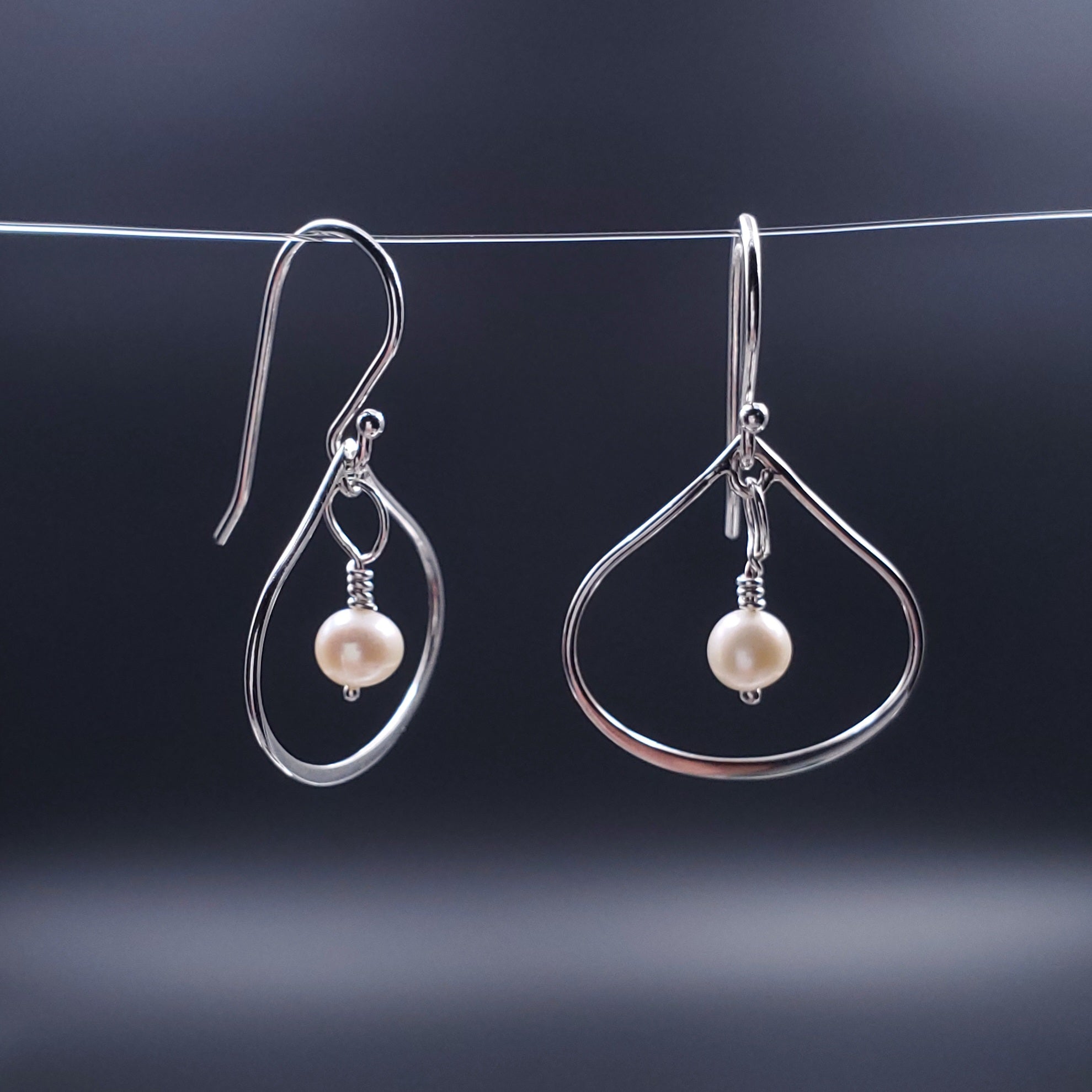 Silver wide teardrop earrings with fresh water pearls dangling in center