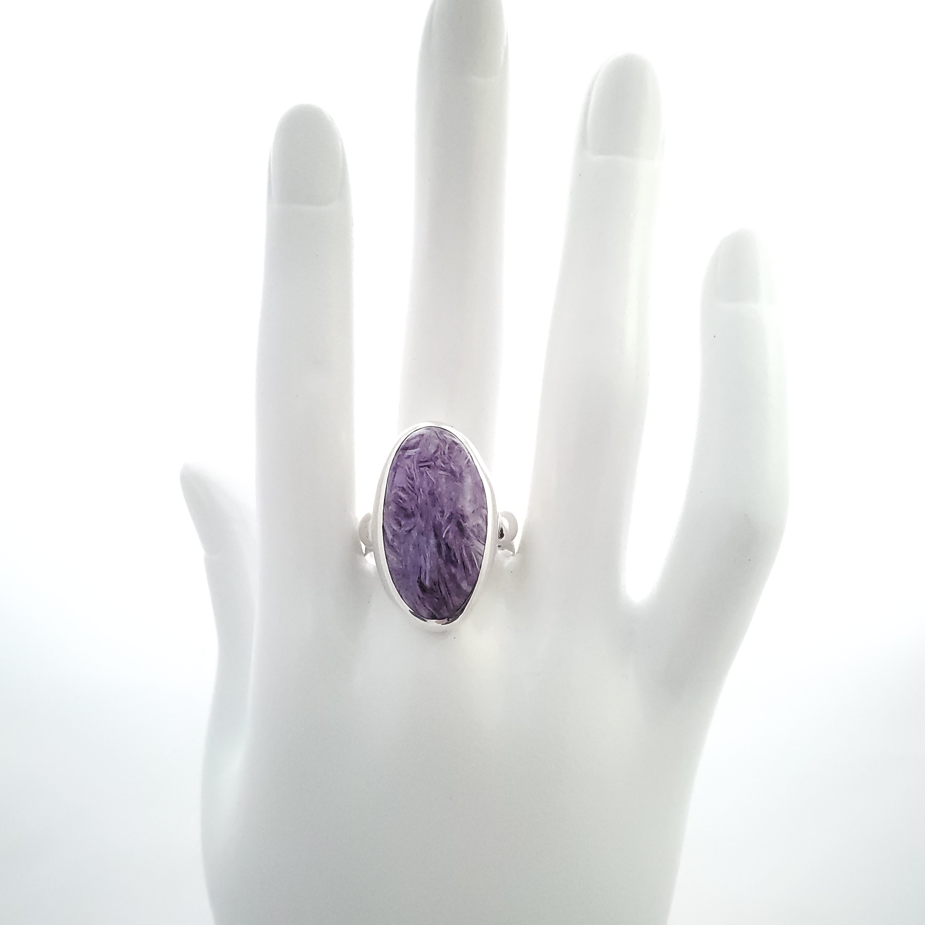 Purple oval charoite silver ring shown on mannequin hand.