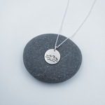 Silver round disc with layers of waves stamped into necklace