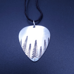 Guitar pick shaped aluminum pendant with trees stamped on it