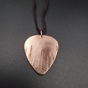 Copper guitar pick shaped pendant with trees stamped on it